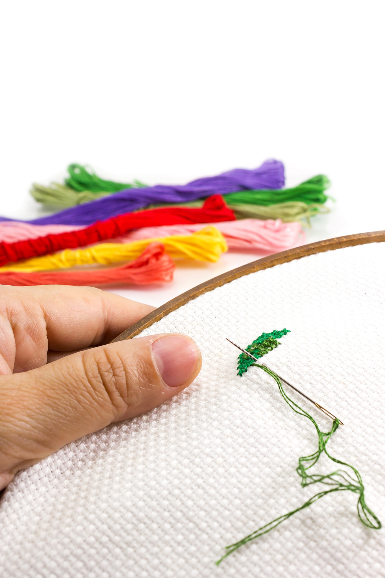 Hands stitching a colorful pattern
